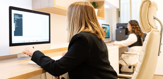 Una mujer sentada en un escritorio frente a un monitor de computadora